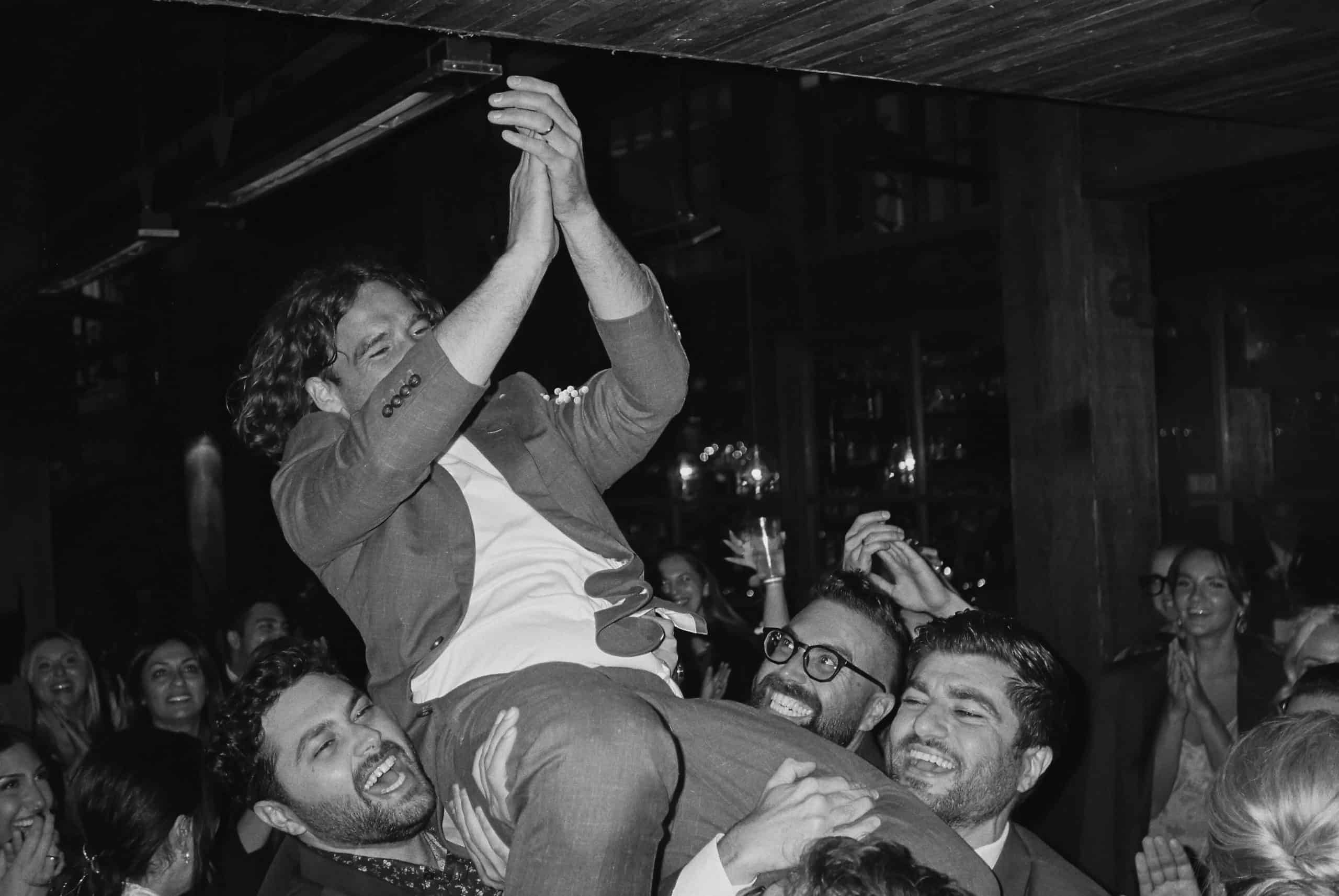 groom is lifted in the air at wedding reception