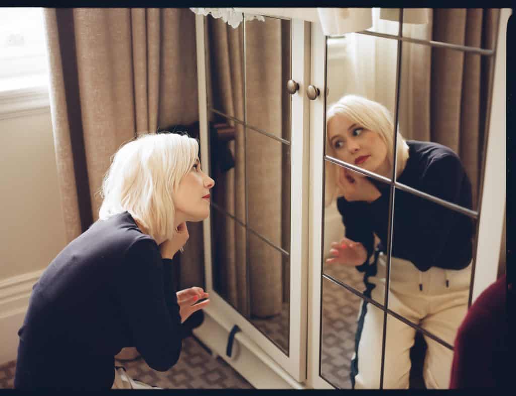 bride puts on make up in front of mirror