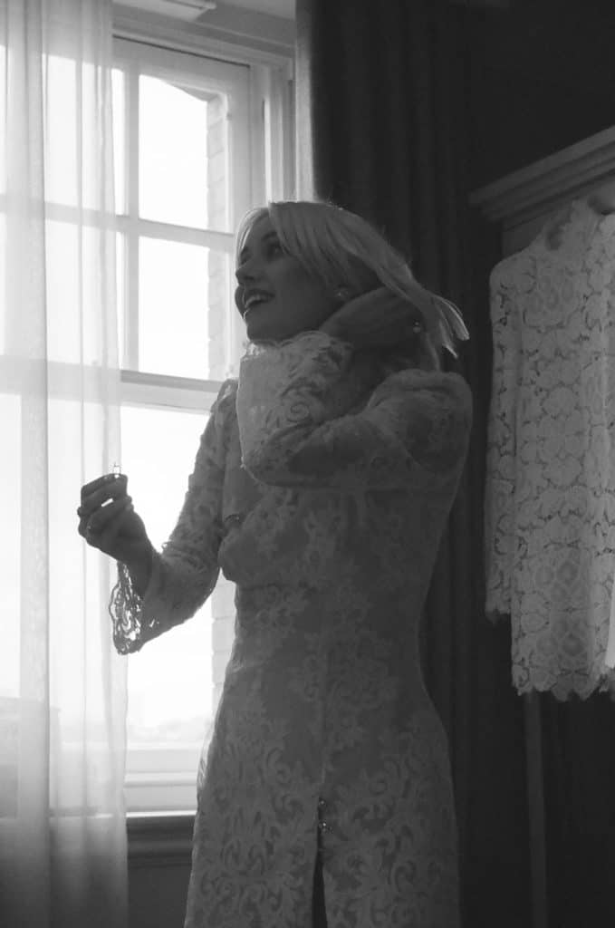 bride puts on perfume on black and white film