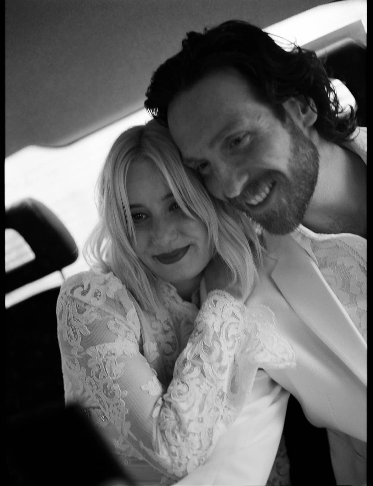 bride and groom in a black cab on black and white film