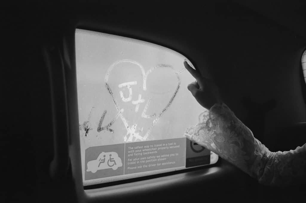 bride writes initials in love heart on black cab window