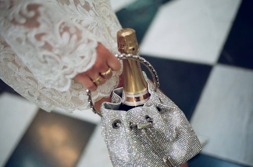 bride holding champagne in her handbag on medium format film