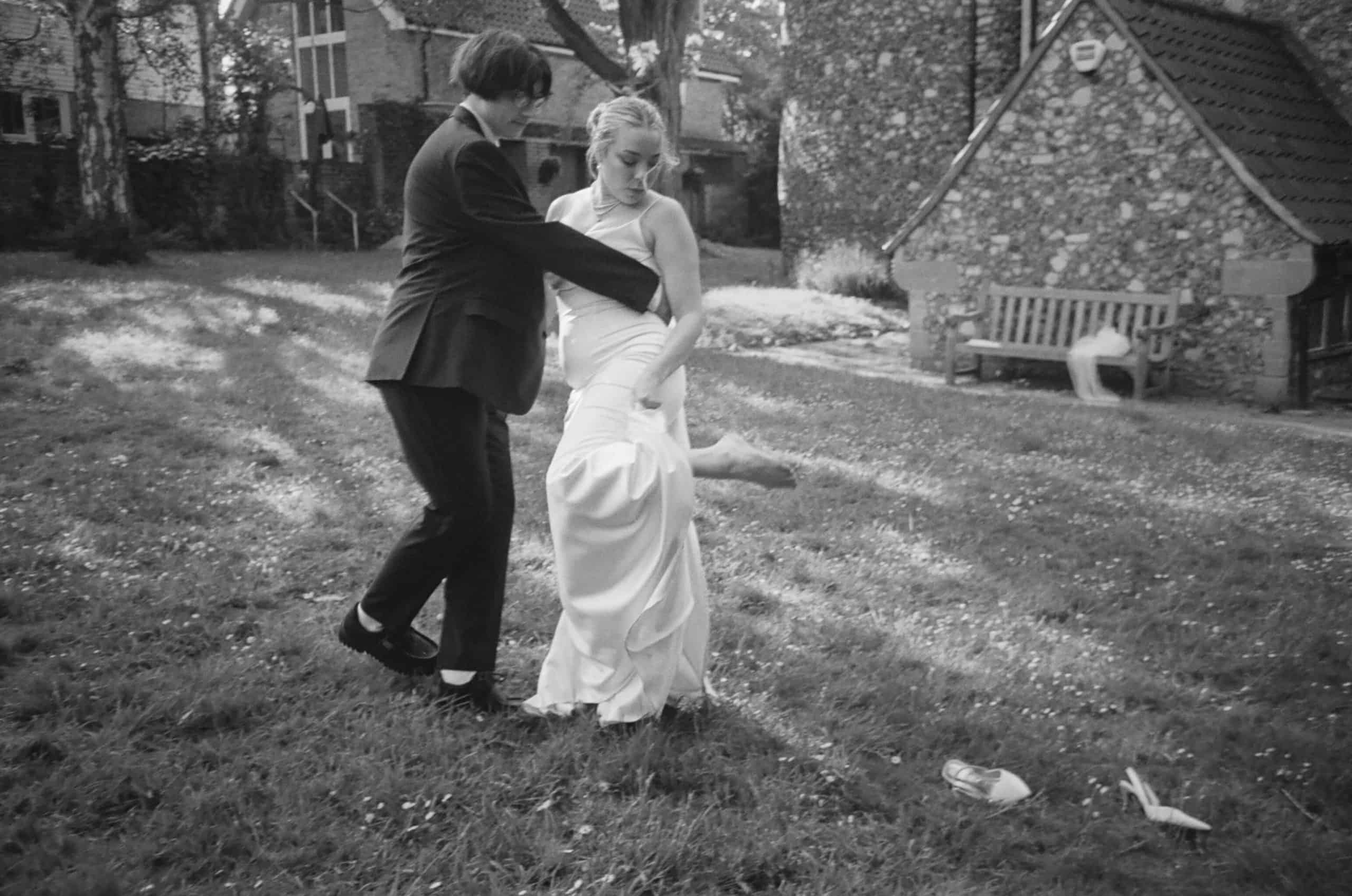 bride kicks off her shoes on black and white film