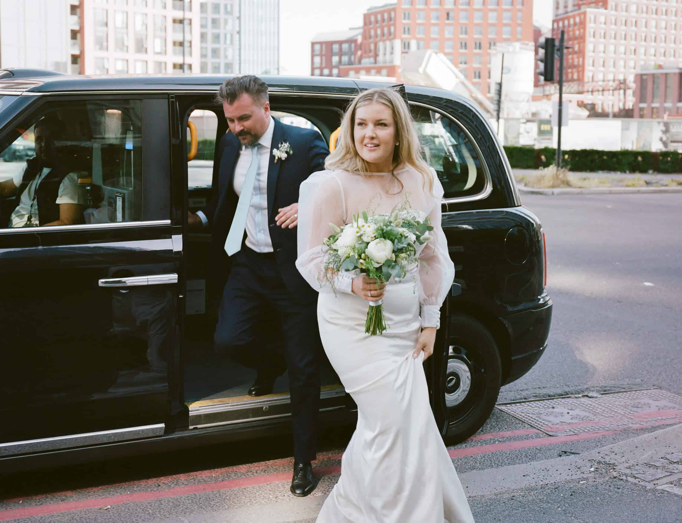 bride and groom in black cab on 35mm